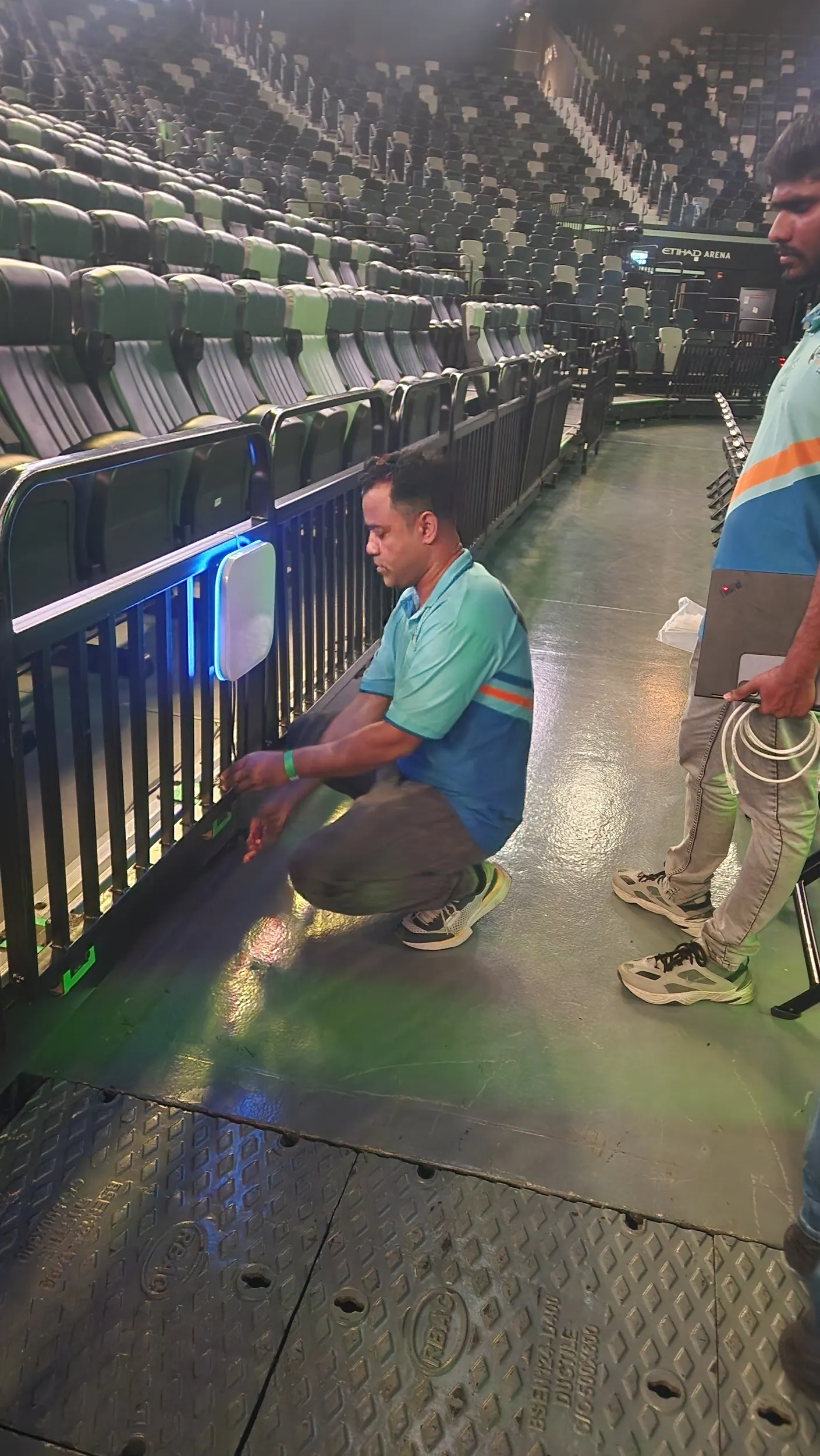 An IP Care engineer installing a WiFi 7 access point on the barrier line in the Etihad Arena bowl