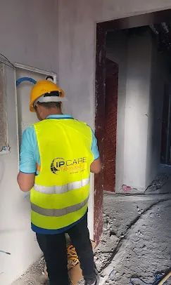 IP Care technician in hard hat and hi-vis vest working at a wall-mounted enclosure on site at Al Jeel Tower